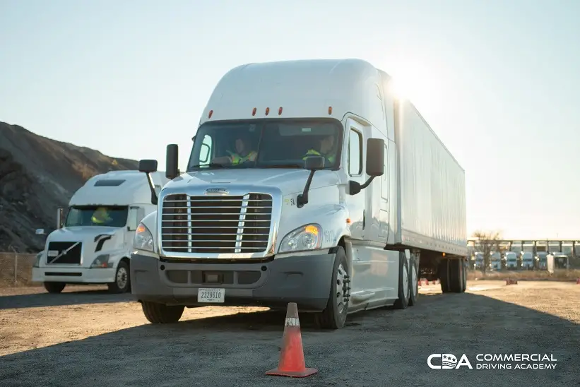 Front of CDA semi truck parked in yard, two instructors inside cab