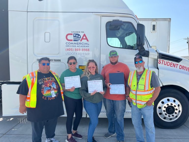 Three CDA graduates and two instructors standing in front of CDA semi truck