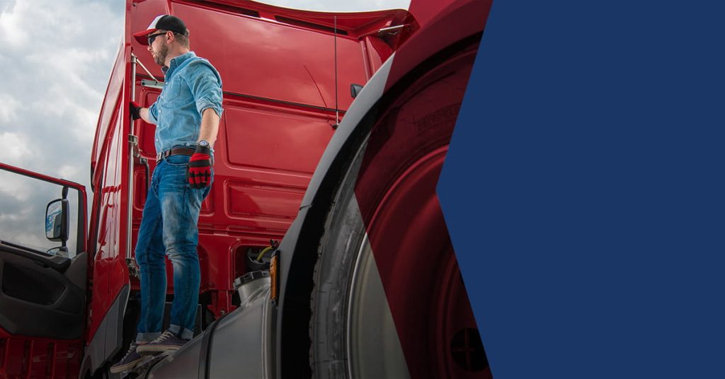 man standing on back of red truck cab holding handle