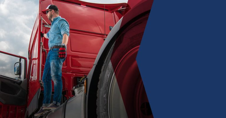 man standing on back of red truck cab holding handle