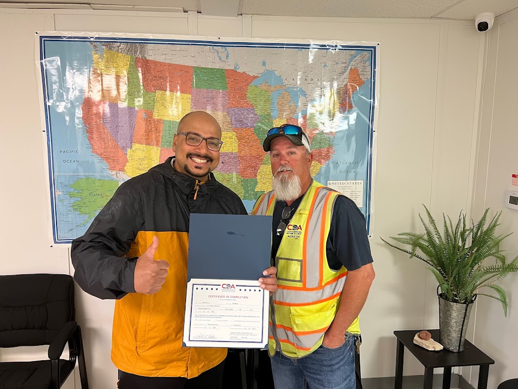 CDA graduate and instructor standing in front of US map in admissions office