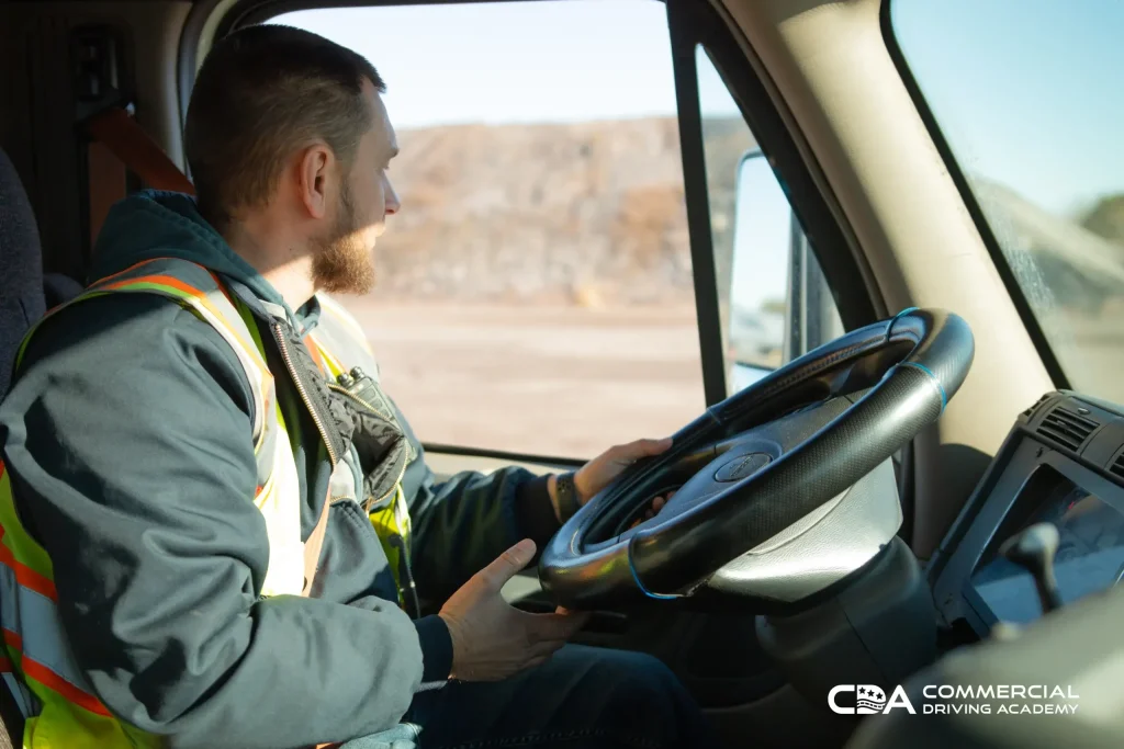 Truck driver sitting behind wheel driving the semi truck. Passenger seat view