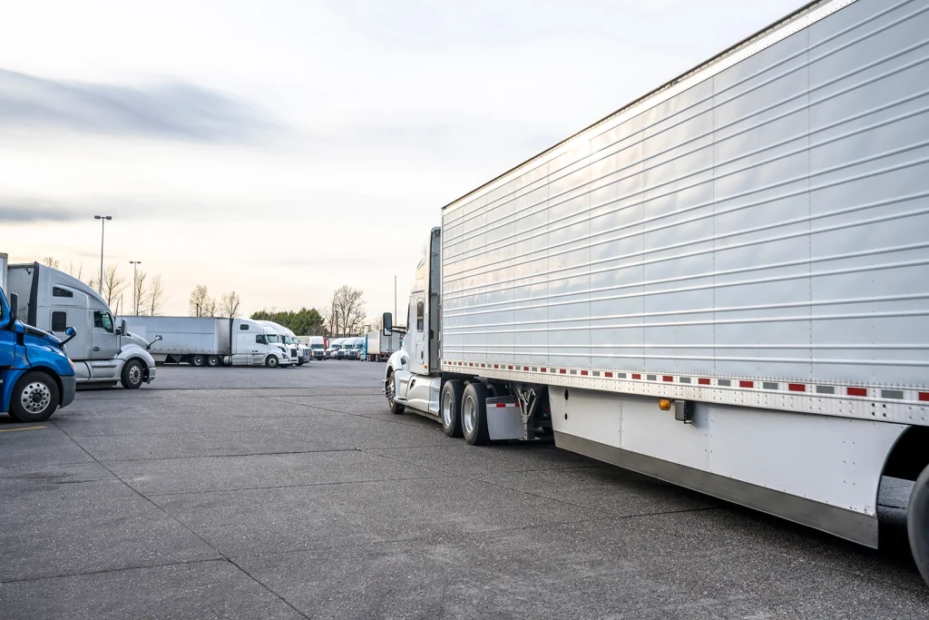 Backside view of a semi-truck trailer, other semis parked on asphalt