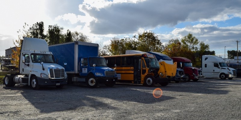 CDA semi trucks, box trucks, and buses parked next to each other in a training yard