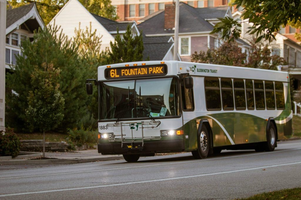 City bus driving down road through neighborhood