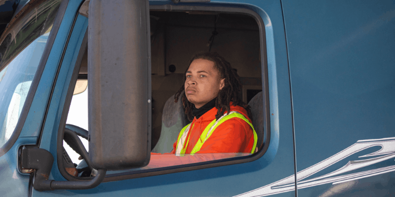 Student trucker sitting behind wheel of semi truck. Close up