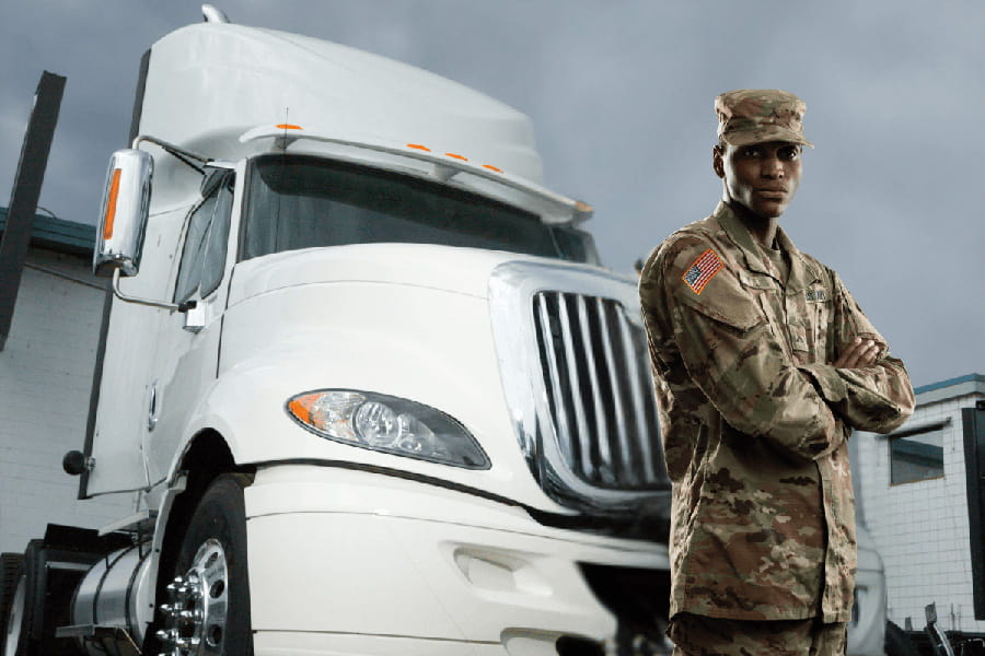 Veteran in uniform standing in front of white semi truck