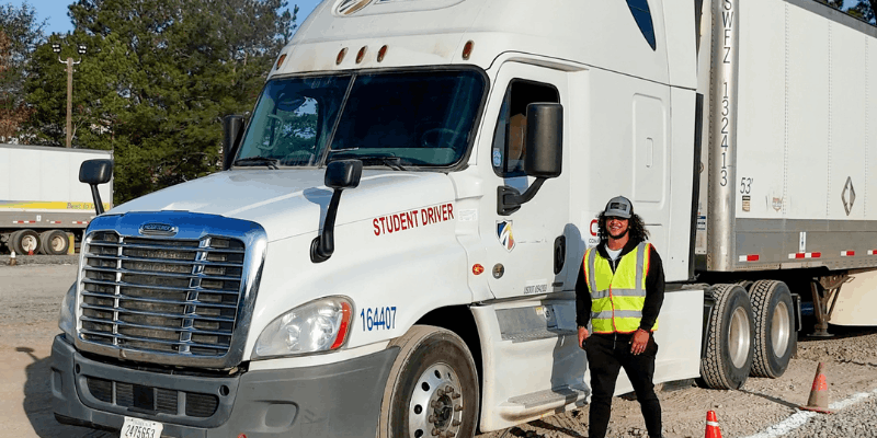 Graduate wearing safety vest standing in front of CDA semi truck