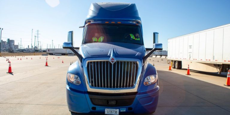 Front view of CDA blue semi truck with a driver and passenger