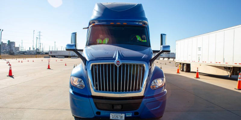Front view of CDA blue semi truck with a driver and passenger