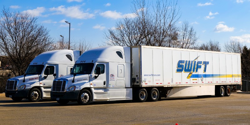 Two CDA Swift semi trucks parked side-by-side in a paved training lot