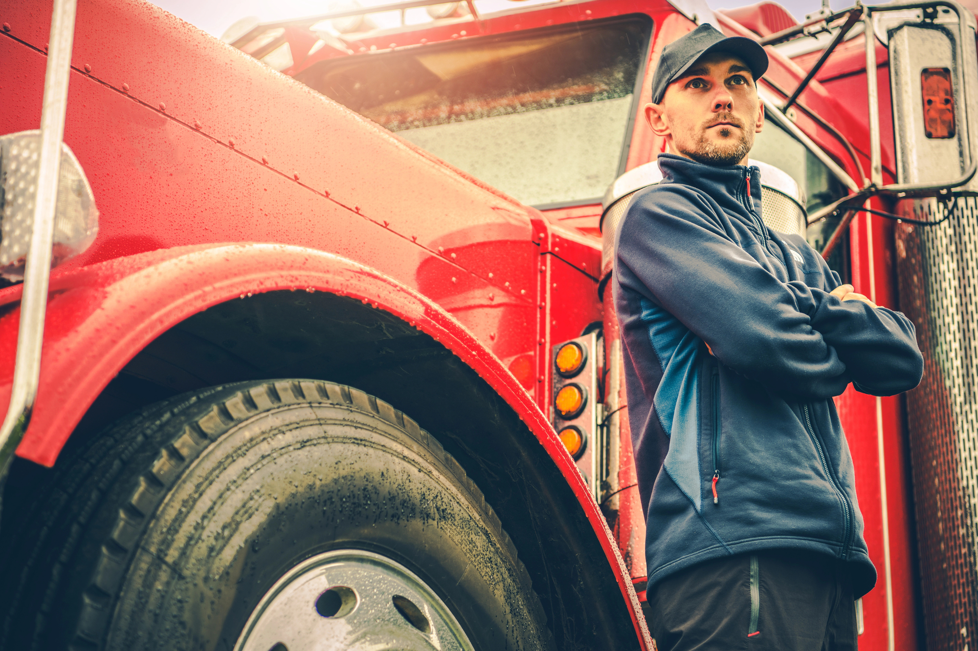 An American commercial truck driver stands beside his truck.